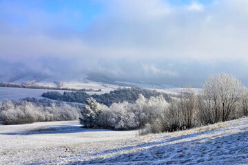 Dramatic  clouds, blue sky in winter landscape with mountains and trees on field nature scenery.