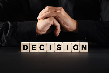 The word decision on wooden blocks with a business person background. Business decision