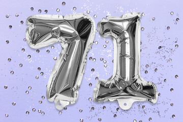 Silver foil balloon number, digit seventy one on a lilac background with sequins. Birthday greeting card with inscription 71. Top view. Numerical digit. Celebration event, template.