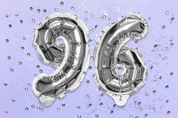 Silver foil balloon number, digit ninety six on a lilac background with sequins. Birthday greeting card with inscription 96. Top view. Numerical digit. Celebration event, template.