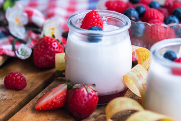 yogurt with wild berries and measuring tape. diet and eating concept