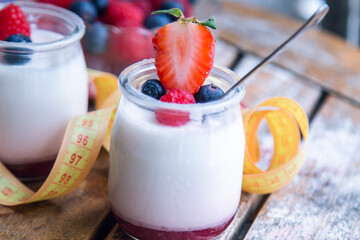 yogurt with wild berries and measuring tape. diet and eating concept