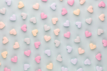 Composition with candy hearts on pastel blue background.