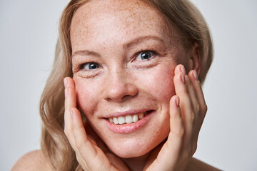 Caucasian freckled woman with naked shoulders and nude makeup