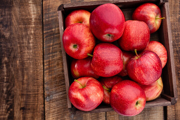 Fototapeta na wymiar Ripe red apples in wooden box. Top view with space for your text.