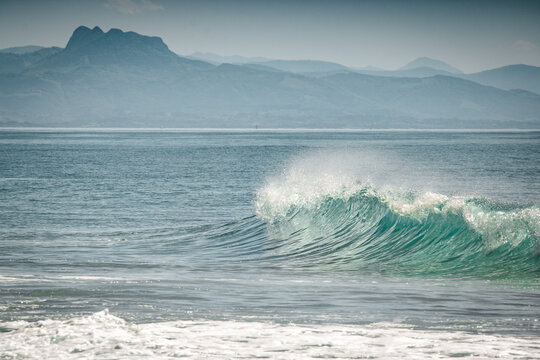 breaking waves in atlantic ocean with mountains in the background in summertime