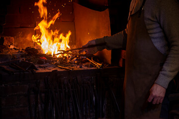 Blacksmith working with open fire in furnace. The blacksmith forging hot iron in workshop
