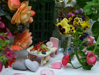 Small dollhouse furniture with beautiful flowers, decorations and berries. Fairies in the garden.