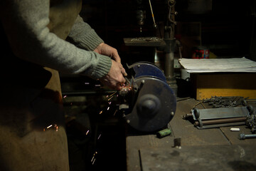 man work in home workshop garage with angle grinder, sanding metal makes sparks closeup, diy and craft concept