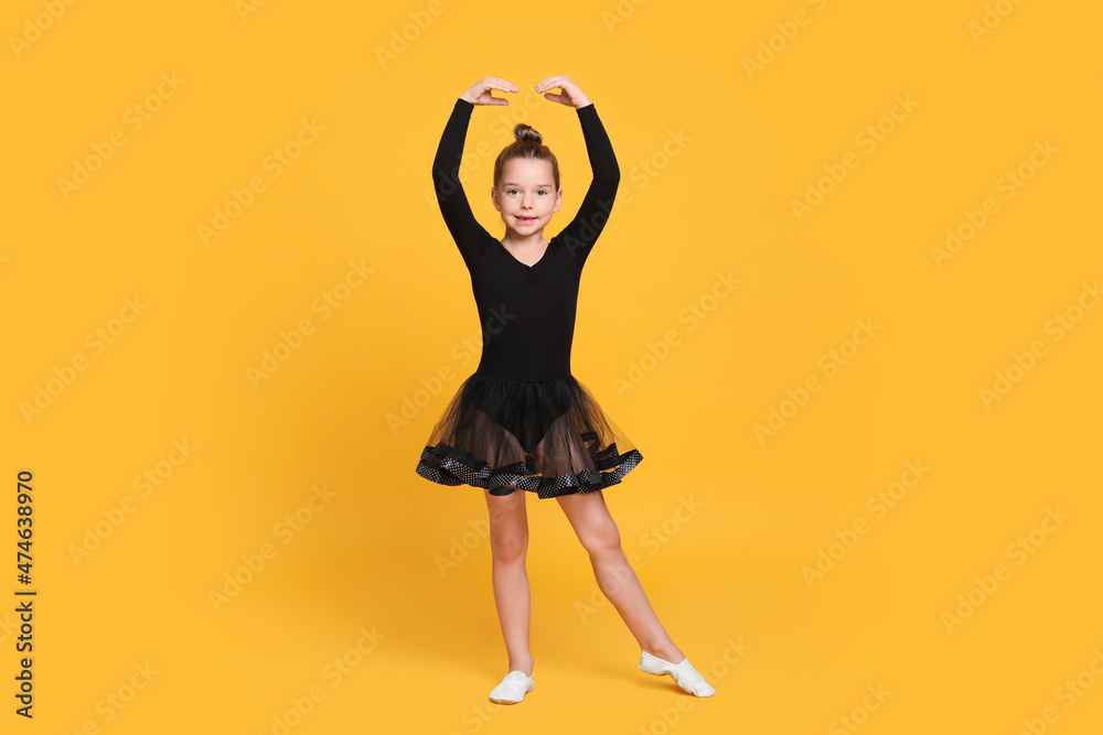 Canvas Prints Cute little girl in black dress dancing on yellow background