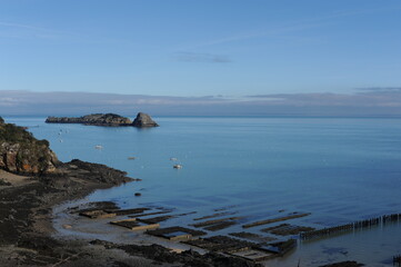 Oyster farm during low tide with blue sky and sea in Cancale, Normandy, France