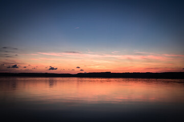 Fototapeta premium Beautiful sunset on the lake, reflection of clouds and moon, background