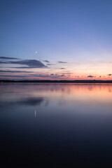 Beautiful sunset on the lake, reflection of clouds and moon, background