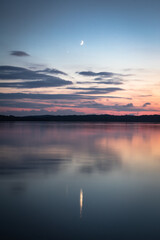 Beautiful sunset on the lake, reflection of clouds and moon, background