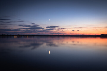 Beautiful sunset on the lake, reflection of clouds and moon, background