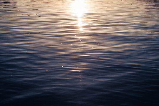 close up of wavy water surface with sun reflection