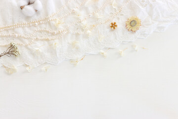 Fototapeta na wymiar Background of white delicate lace fabric, dry flowers and pearls