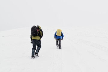 Hikers in winter mountains, bad weather - 474642116