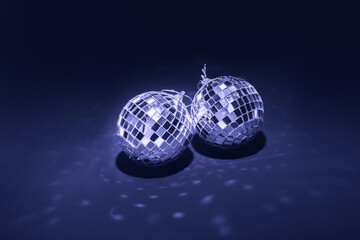 two mirror balls illuminated by bright light on dark violet background