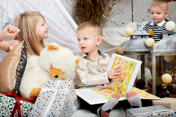 Three children kids sitting between Christmas gift boxes in a decorated house.Merry Christmas and Happy Holidays!