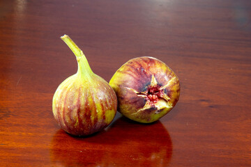 Fototapeta premium Isolated ripe fig (Ficus carica), on rustic wood table with reflection