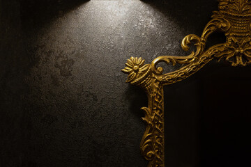 A vintage mirror with a golden frame hung on a dark wall - 474643701