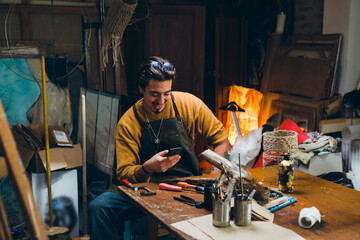 man using smartphone in his workshop