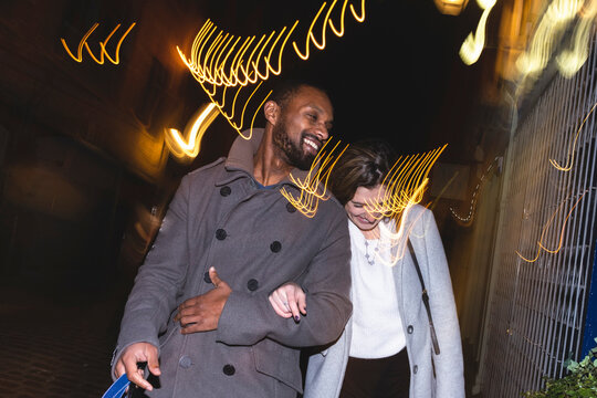 Happy Couple In Trench Coats Walking At Night