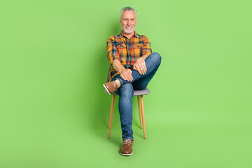 Full body photo of funky old beard man sit wear shirt jeans footwear isolated on green color background