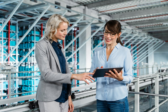 Businesswoman having discussing with coworker over tablet PC at factory - Powered by Adobe