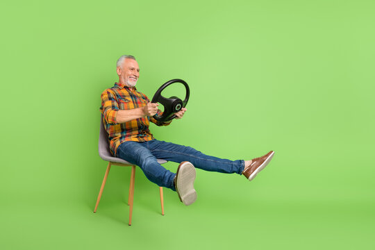 Full size photo of cool elder beard man sit drive car wear shirt jeans shoes isolated on green color background