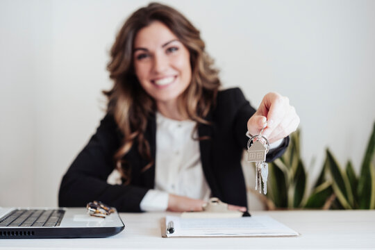 Smiling saleswoman holding house keys at office