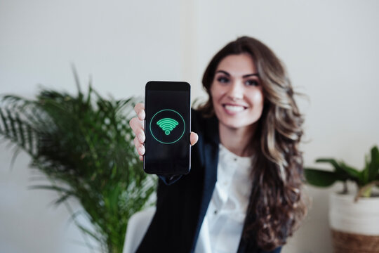 Businesswoman showing smart phone with wifi logo