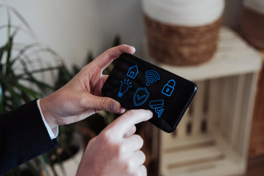 Businesswoman holding smart phone with home automation icons