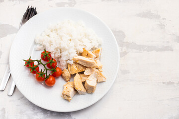 chicken breast with boiled rice and tomato on white plate