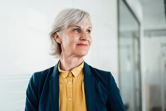 Smiling senior businesswoman looking away in office