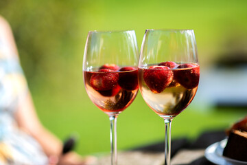Two glasses white wine with red strawberries on green summer background