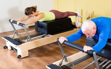 Elderly man doing exercises at physiotherapy clinic - revitalizing gym exercises