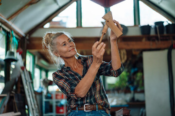 Woman holding wooden tool at garden shed