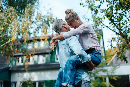 Man carrying cheerful woman at backyard