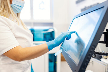 Modern technology in the lab. A nurse is standing next to a machine for analyzing blood samples and...