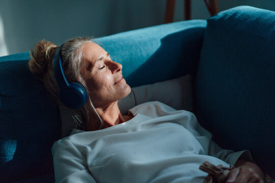 Woman listening music through wireless headphones at home
