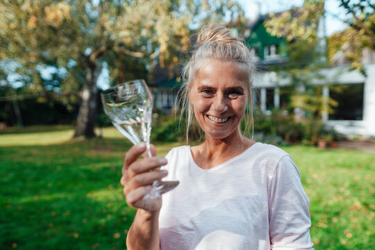 Happy woman holding champagne flute at backyard