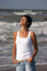 Fototapeta premium Young beautiful woman with closed eyes on the background of the stormy sea.
