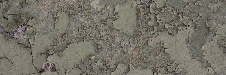 Peeling paint on the wall. Panorama of a concrete wall with old cracked flaking paint. Weathered rough painted surface with patterns of cracks and peeling. Wide panoramic grunge texture for background