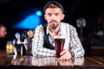 Expert Female bartender adds ingredients to a cocktail while standing near the bar counter in pub