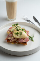 Ham and poached egg waffle, restaurant gourmet breakfast on big white dish