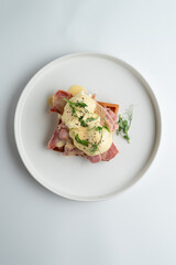 Prosciutto and poached egg waffle, appetizing photo, top view on white restaurant table