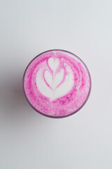 Above view of pink matcha latte with latte art on delicate milk froth, white background, copy space