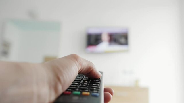 Close-up of switching channels tv. Person watching smart TV and uses remote control.